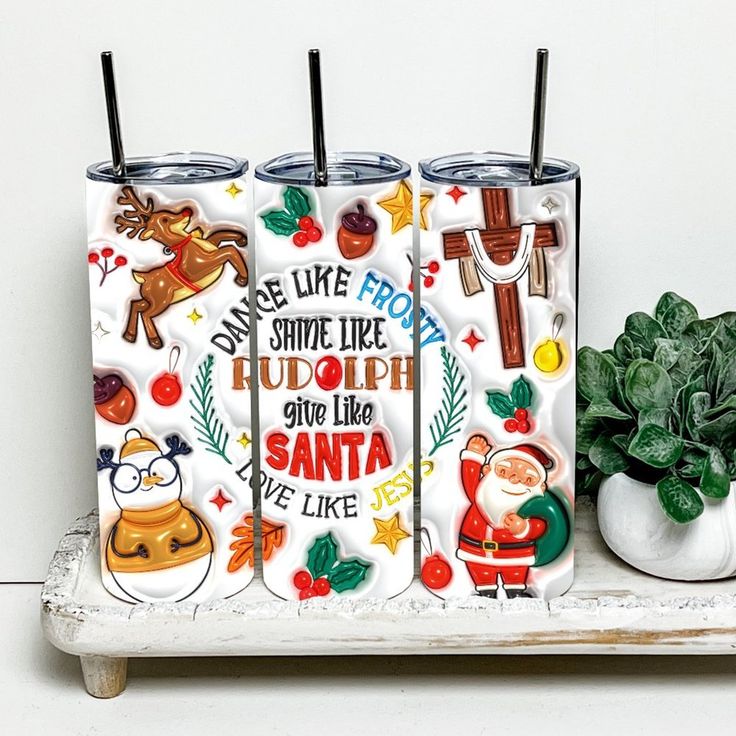 three tumblers sitting on top of a white shelf next to a potted plant