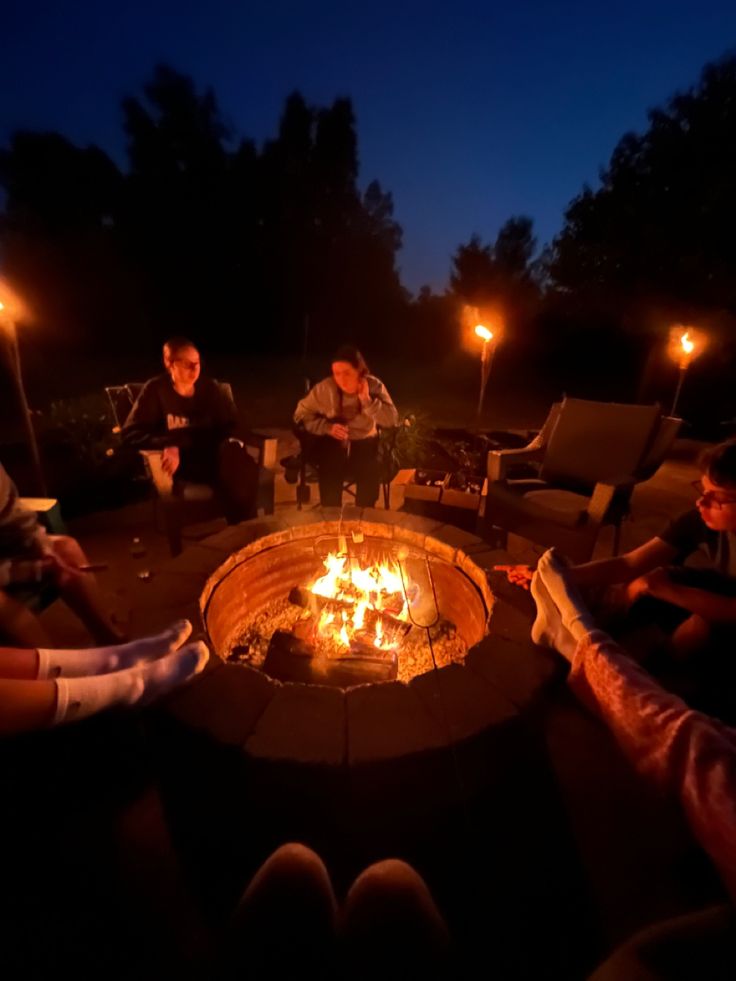 people sitting around a fire pit at night