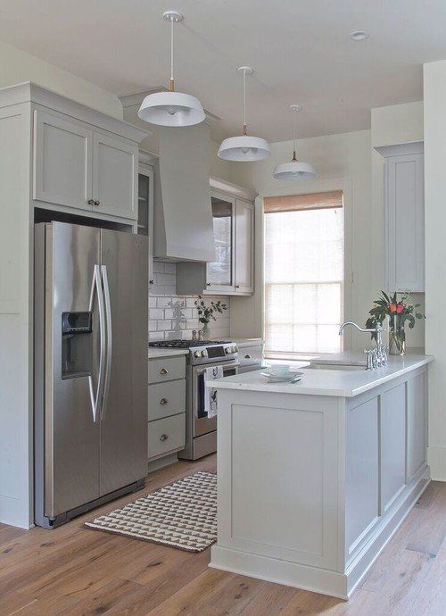 a kitchen with white cabinets and stainless steel appliances in the center, along with an area rug on the floor