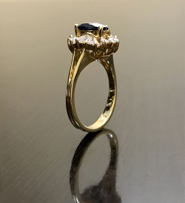 DeKara Designs Clearance Metal- 14K Yellow Gold, .583. Stones- 1 Pear Shape Ceylon Blue Sapphire 1.48 Carats, 10 Long Baguette Diamonds F-G Color VS1 Clarity 0.40 Carats, 7 Round Diamonds F-G Color VS1 Clarity 0.30 carats. Size- Ring is a 6, and could be sized up or down at no additional cost! FREE SIZING Art Deco Inspired Handmade 14K Yellow Gold Ceylon Blue Sapphire Halo Diamond Ring. This ring is inspired by the Art Deco era with an enticing fiery pear shaped Ceylon Blue Sapphire. The sapphir Timeless Yellow Gold Sapphire Wedding Jewelry, Formal Emerald Cut Sapphire Cluster Ring, Luxury 14k Gold Sapphire Ring For Anniversary, Heirloom Yellow Gold Sapphire Ring With Halo Setting, Yellow Gold Emerald-cut Sapphire Diamond Ring, Luxury Yellow Gold Sapphire Cluster Ring, Luxury 14k Gold Sapphire Wedding Ring, Emerald Cut Sapphire Diamond Ring In Yellow Gold, Luxury Yellow Gold Sapphire Ring With Halo Setting