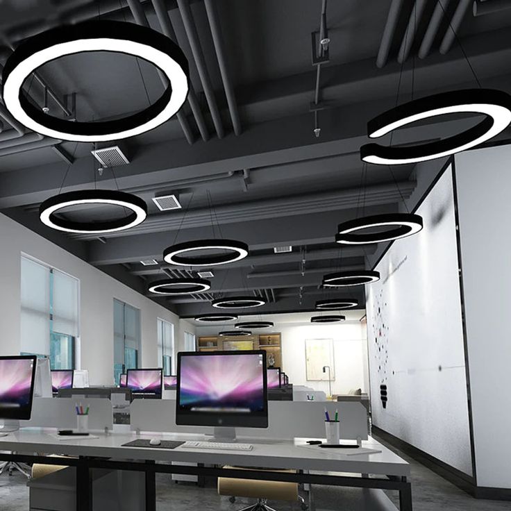 an office with multiple monitors and lights on the ceiling