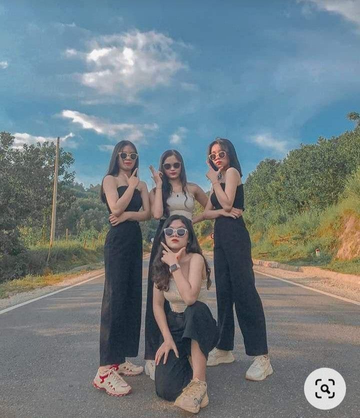 three women standing on the side of a road with their arms around each other, posing for a photo