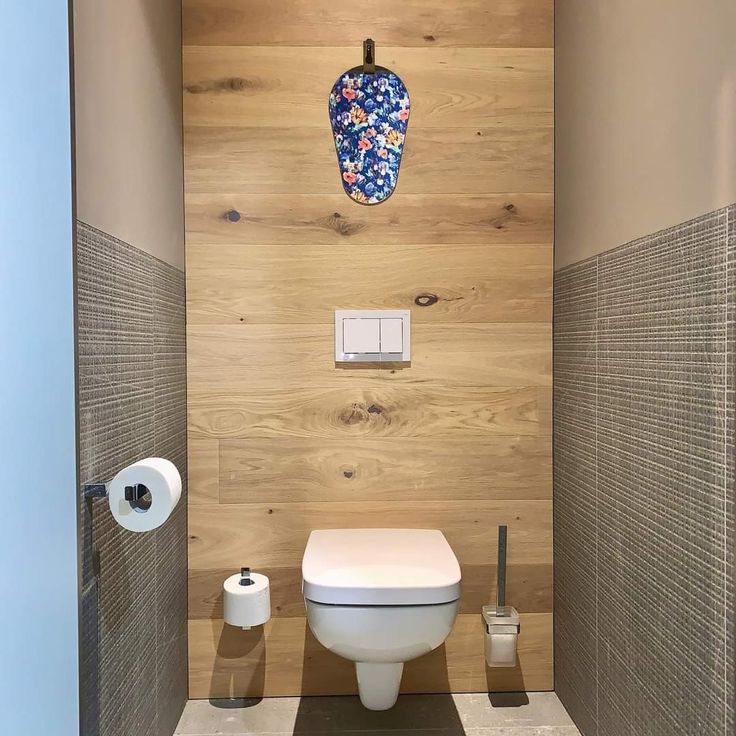 a toilet in a bathroom with wood paneling on the walls