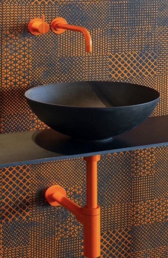 an orange faucet is mounted to the wall next to a black bowl sink