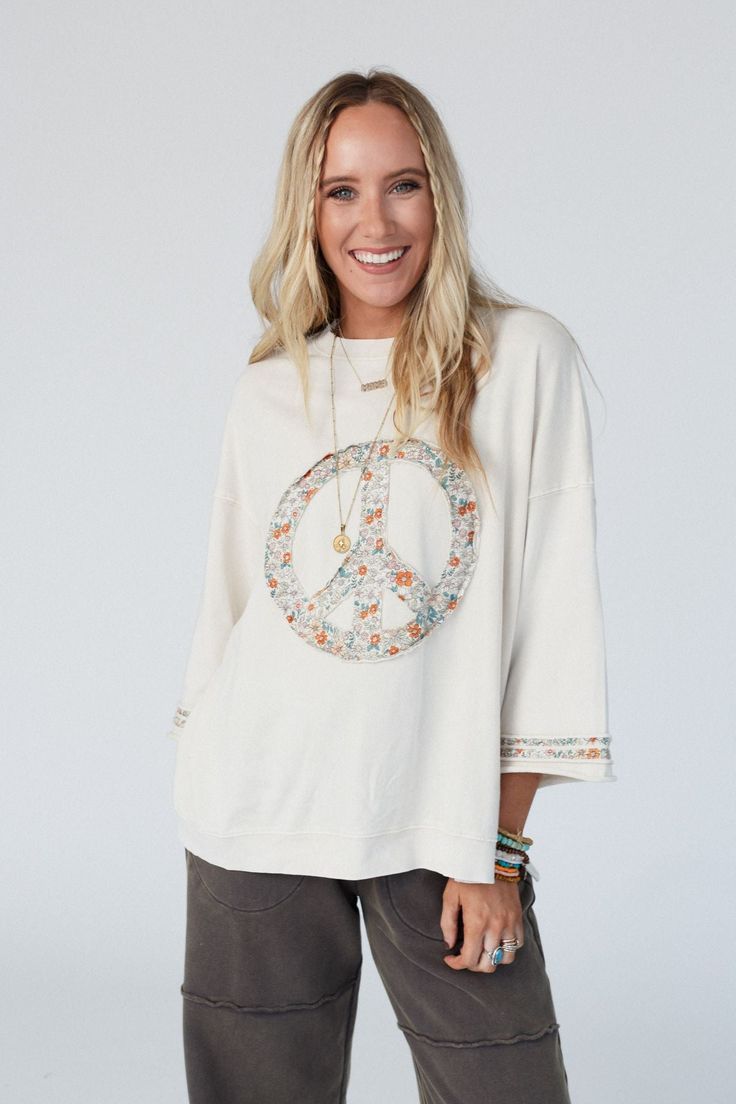 Comfy and cozy, yet with a style that's ideal all year round is the Beatrix Pullover! This will quickly become your go-to because it features: Comfortable and cozy, mineral-washed, terry knit fabric Loose and oversized pullover silhouette Classic crew neckline Dropped shoulders with loose 3/4 length sleeves Contrast floral printed fabric along the edges and center-front peace sign Ribbed trim along the neckline and bottom edges Raw edges and side slits for added boho style and comfort Wear this