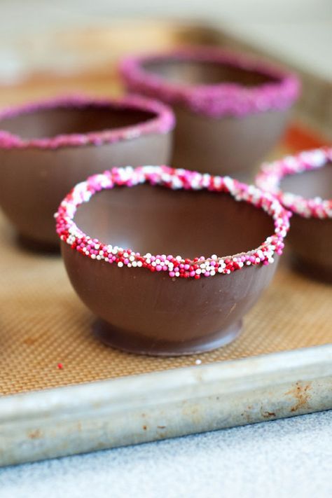 four chocolate cups with sprinkles in them are sitting on a tray, ready to be decorated