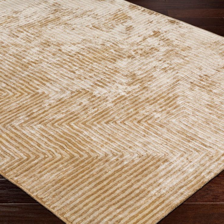 a brown and white rug on top of a wooden floor with dark wood floors in the background