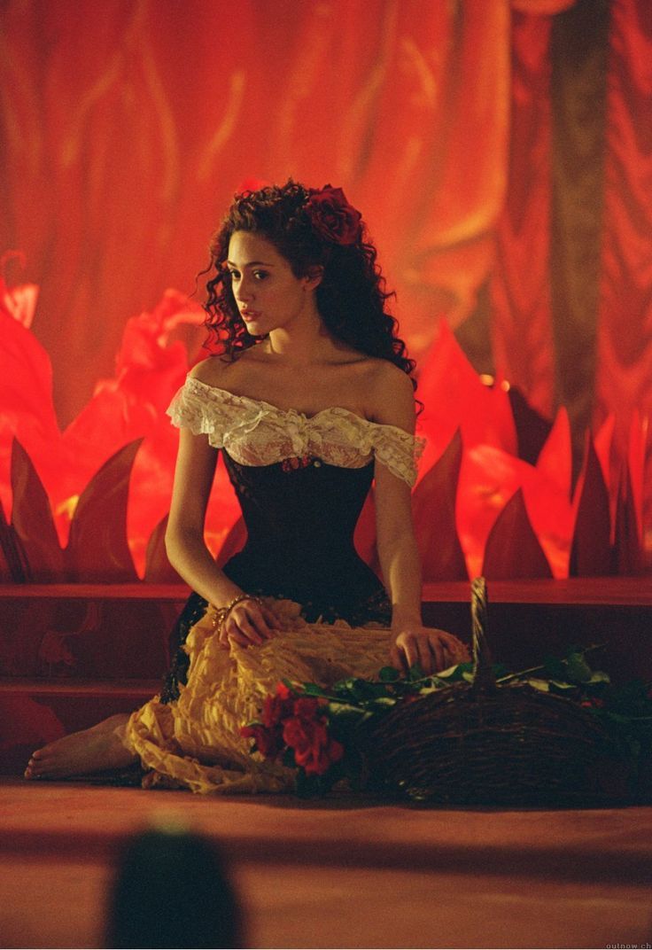 a woman in a black and yellow dress sitting on the floor next to a basket