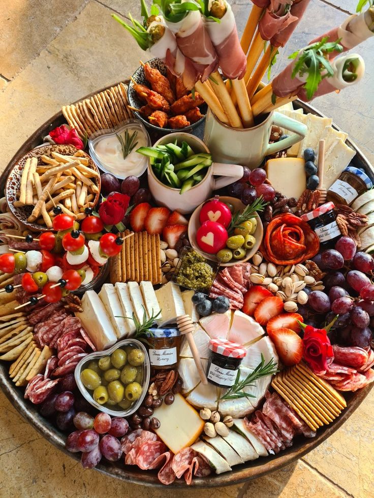 a platter filled with different types of cheeses, meats and vegetables on top of a table