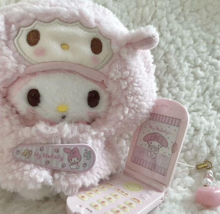 a hello kitty stuffed animal next to a cell phone and keychain on a white carpet