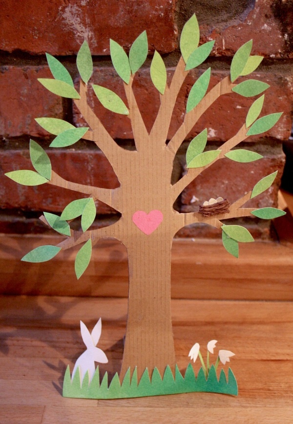 a paper cut out of a tree with an easter bunny sitting under it on the ground