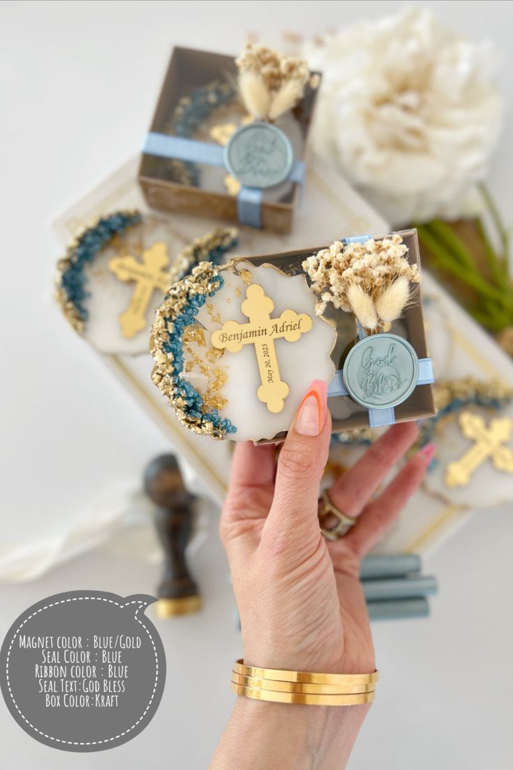 a person holding up some small cookies in front of a white rose and blue ribbon