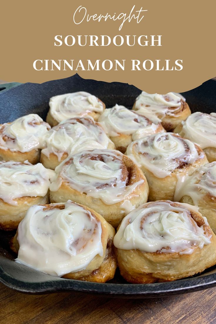 cinnamon rolls in a cast iron skillet on a wooden table with text overlay that reads overnight sourdough cinnamon rolls