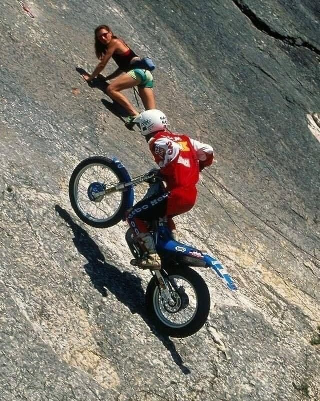 a man riding on the back of a dirt bike down a rocky slope next to a woman