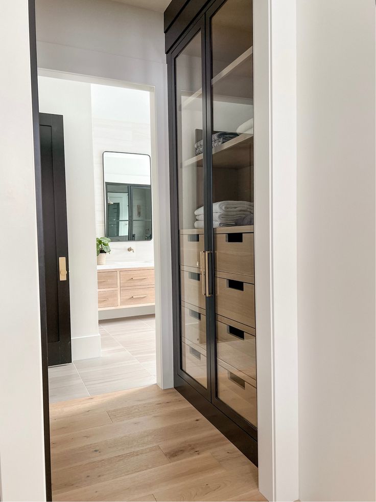 an empty room with wooden floors and glass doors leading to another room in the background