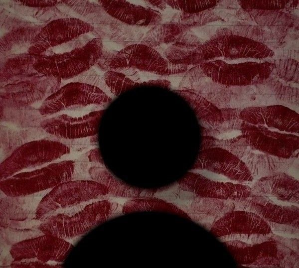 two black circles on a red and white background with lipstick imprints in the middle