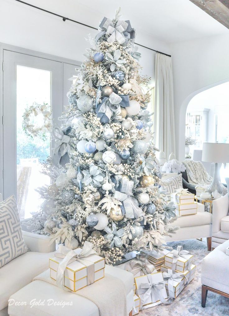 a decorated christmas tree in a living room with silver and white ornaments on the top