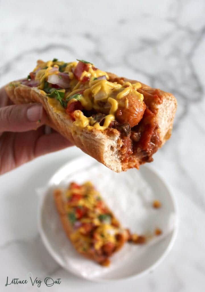 vegan chili dogs on a plate being held up to the camera by a hand