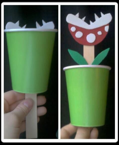 a hand holding a green cup with a red flower on the top and a white crown on the bottom