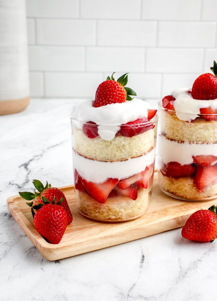 strawberry shortcakes with whipped cream and fresh strawberries on a wooden cutting board