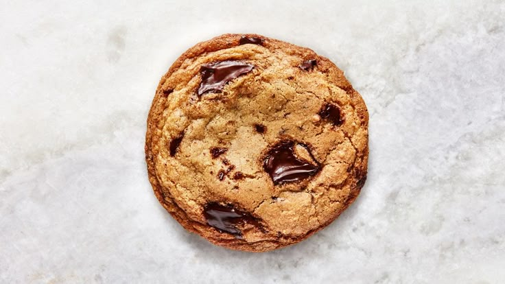 a chocolate chip cookie sitting on top of a white counter