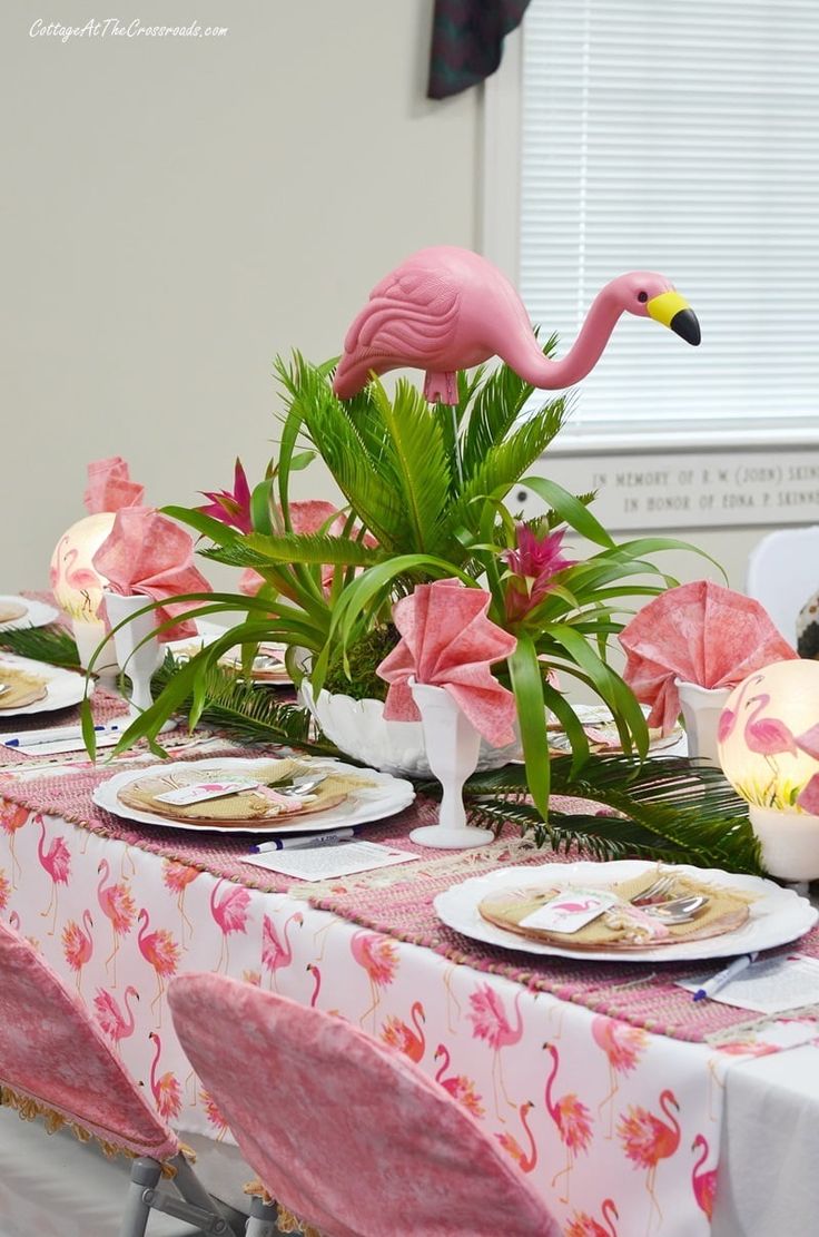 the table is set with pink flamingos and flowers