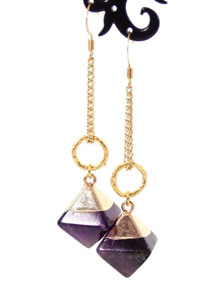 Clip-on style also available! These unique dangle stone earrings make a stunning statement! Semi precious Amethyst stone pendants coupled with 10k gold plated textured rings give these beauties a chic look with a luxurious feel! 18k gold plated wire earring hooks add a delicate touch, completing the earrings!Product De 14k Gold Filled Jewelry With Gemstone Accents, Modern Purple Dangle Jewelry, Gold Amethyst Drop Earrings, Elegant Gold Amethyst Jewelry, Modern Dangle Jewelry With Gemstone Accents, Gold Plated Earrings With Gemstone Accents, Modern Amethyst Gemstone Earrings, Modern Long Drop Gemstone Jewelry, Modern Purple Metal Jewelry