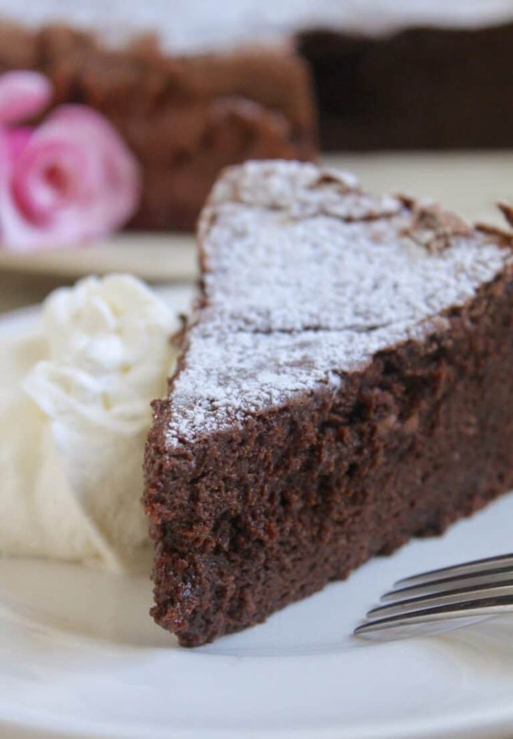 a piece of chocolate cake on a white plate with a fork and some whipped cream