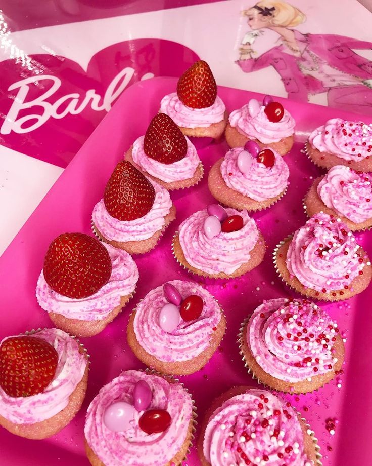 cupcakes with pink frosting and strawberries are arranged in a heart - shaped tray