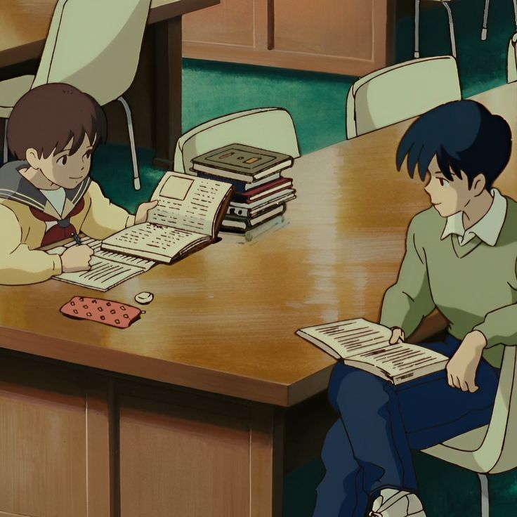 two people sitting at a table with books