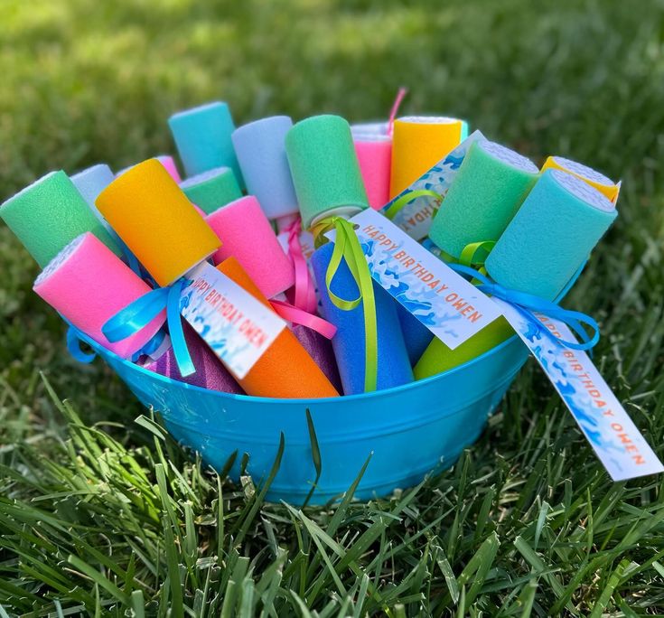 a blue bucket filled with lots of different colored sand and water toys on top of green grass