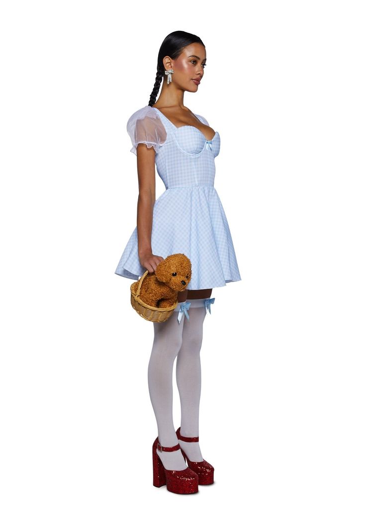 a woman in a white dress and red shoes is holding a teddy bear while standing