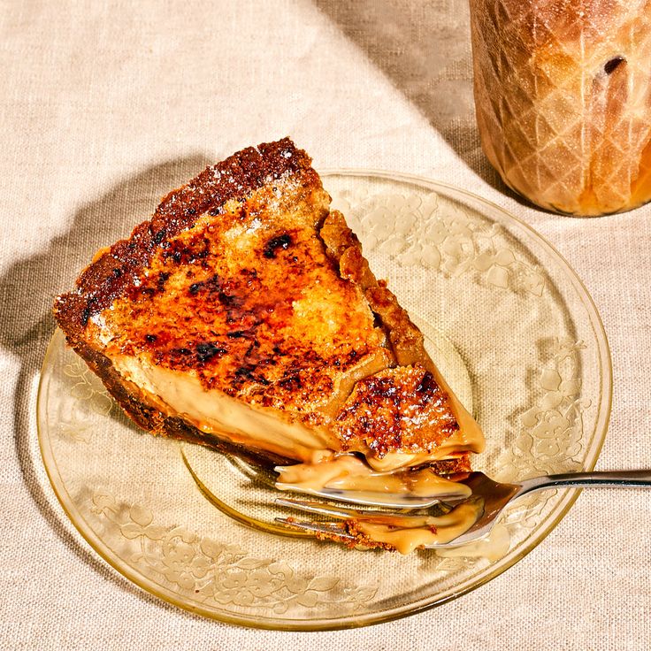 a piece of cake on a plate with a fork and glass jar in the background