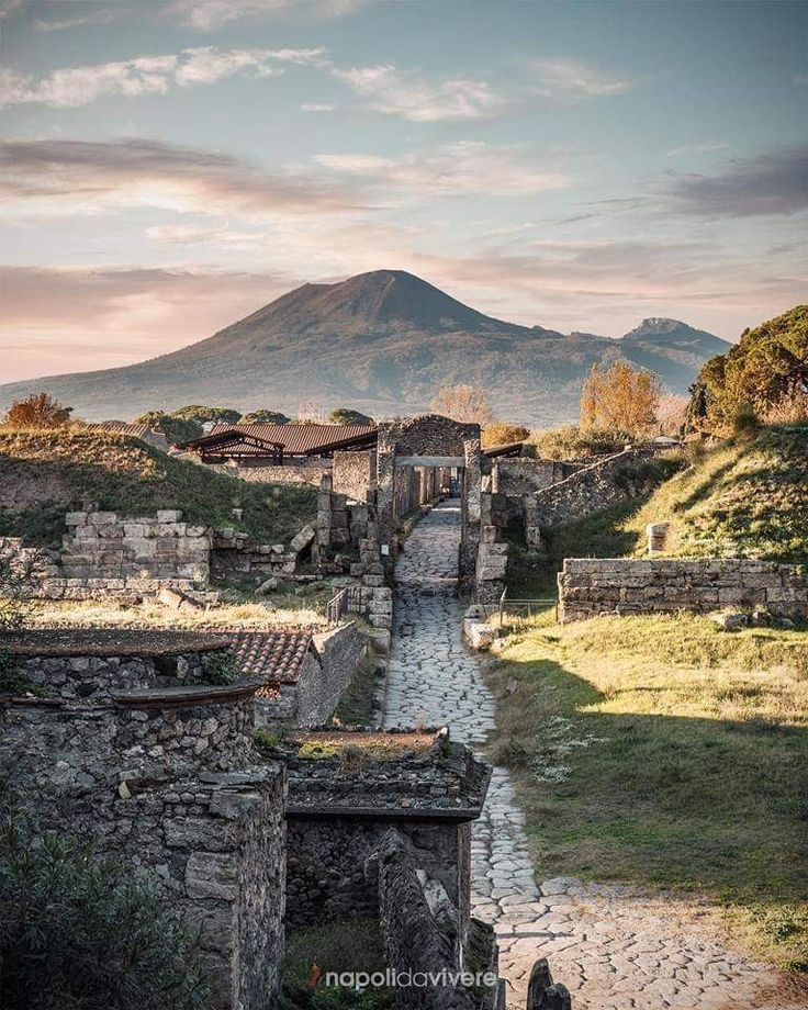 an old town with a river running through it and a mountain in the back ground