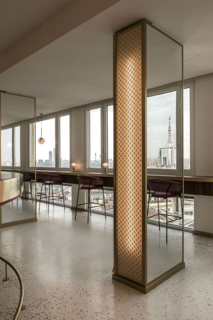 an empty room with tables and chairs in front of large windows that look out onto the city