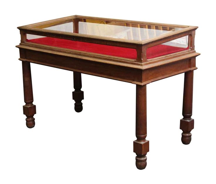 a wooden table with a glass top and red velvet under the bottom shelf on wheels