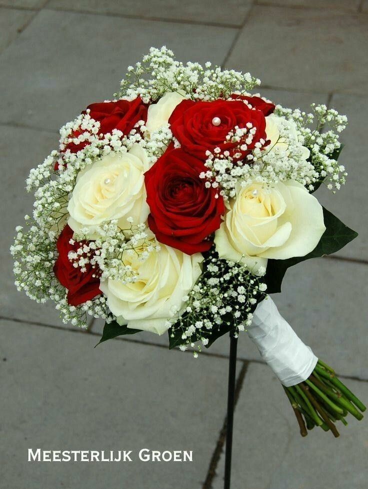 a bridal bouquet with red and white roses on a pole in front of a sidewalk