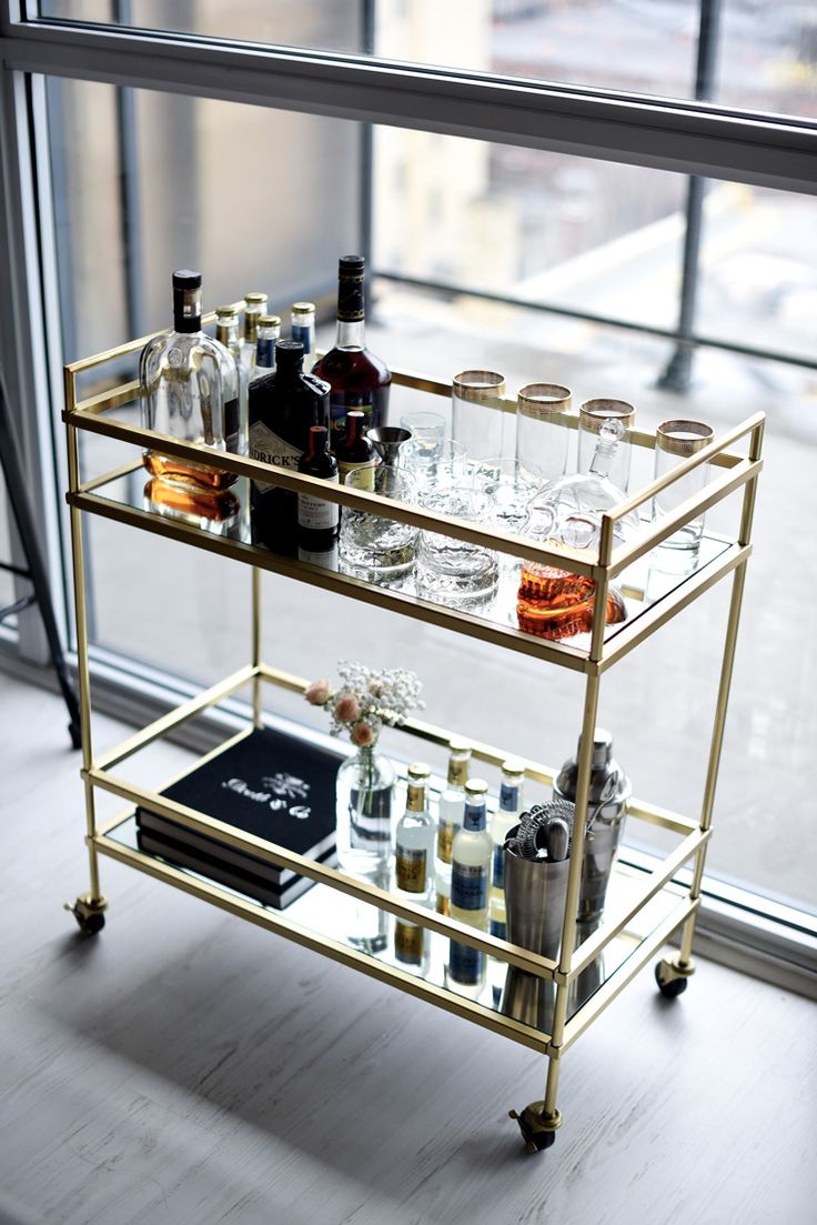 a gold bar cart with drinks on it in front of a window and the words, 12 best bar cart ideas - how to use one