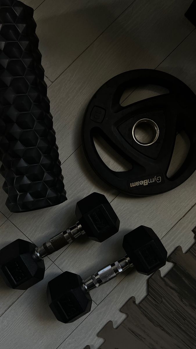 there are three black dumbs on the floor next to a pair of exercise equipment