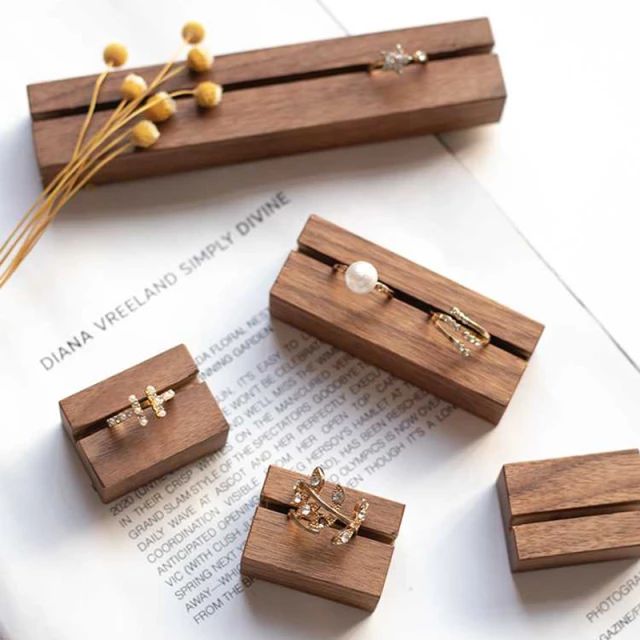 five wooden boxes with rings on them sitting on top of an open book next to some dried flowers