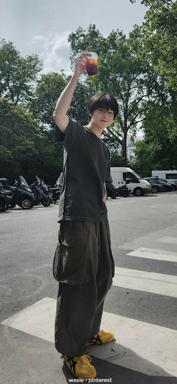 a young man is standing in the street with his hand up and holding an apple above his head