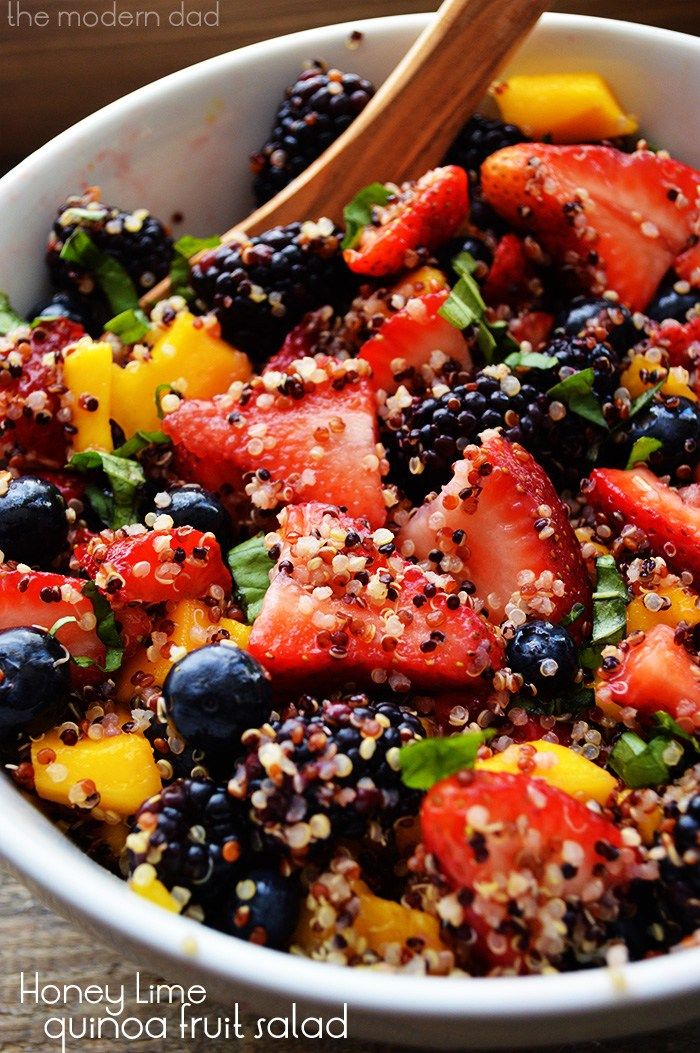 a salad with strawberries, blueberries, and other fruits is in a white bowl