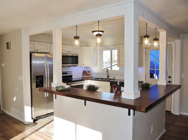 a kitchen with an island in the middle and two lights hanging from it's ceiling