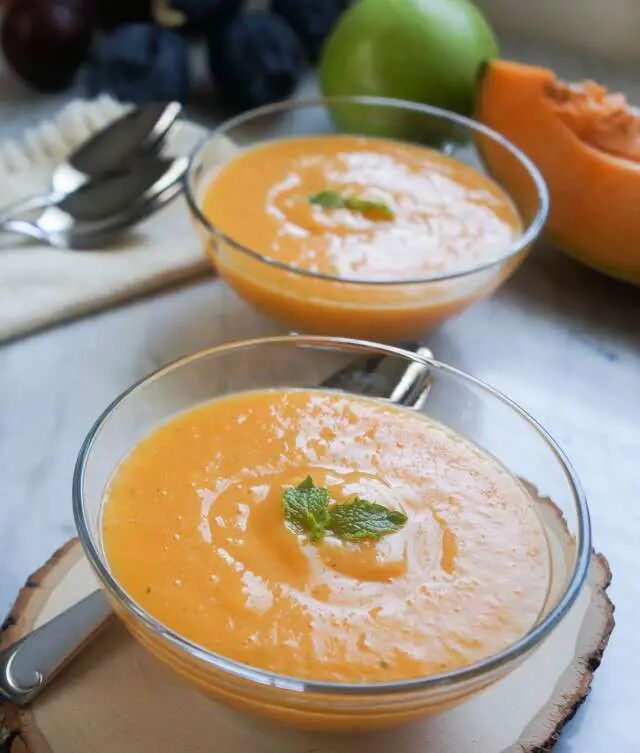 two bowls filled with carrot soup on top of a table