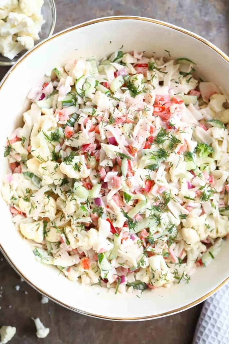 a white bowl filled with coleslaw salad next to a fork and spoon on a table