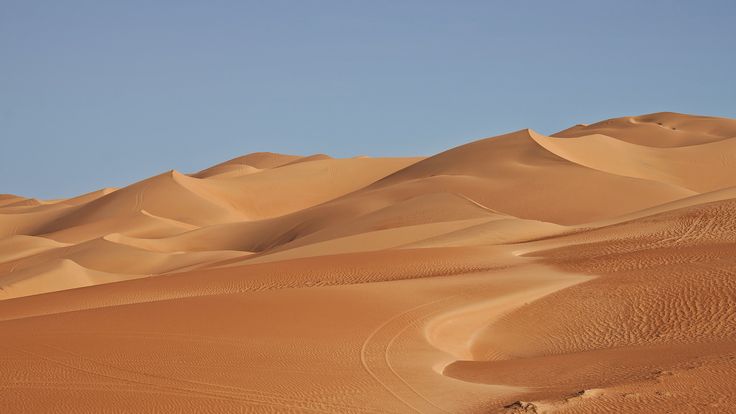 the desert is covered in sand dunes and blue skies