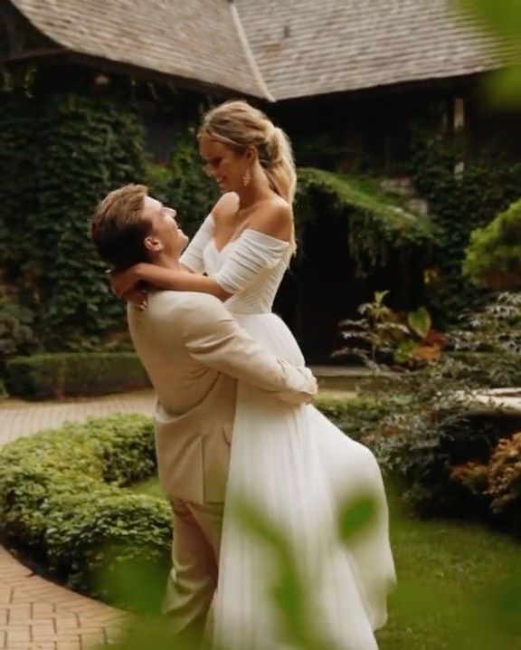 a woman in a white dress is hugging a man