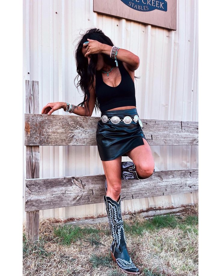 Nashville Black Skirt Outfit, Black Leather Skirt And Cowboy Boots, Black Leather Skirt Outfit Western, Black Skirt Nashville Outfit, Black Denim Country Outfit, Country Concert Black Boots, Country Leather Skirt Outfit, Leather Skirt With Cowgirl Boots, Black Leather Shorts Concert Outfit