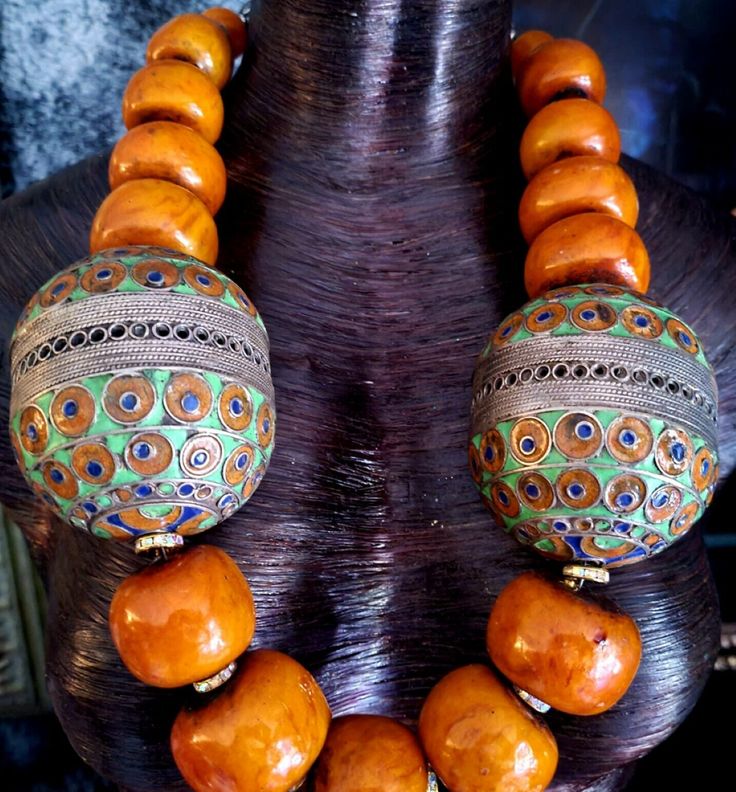 If you are seeking a piece with that massive WOW FACTOR, this Moroccan Resin Tribal Necklace is for you!! This Huge Berber Egg Ethnic Chest Piece features the large and scarce metal Berber Egg beads with 6" circumference, each. The Moroccan Resin Beads (average = 1.5" x 1.25") are a warm soft caramel or brown-orange and are separated from one another with Aurora Borealis Rhinestone Rondelles adding brilliance and light. This Oversized Beaded Statement Necklace will lay best on a smaller busted woman, since it pulls/rolls to the left or right with fuller busts. Ideally, these Bold Chunky Heavy Men's Warrior Beads will sit best on a male torso. The Boho Couture Neck Candy is finished with Tibetan Resin Capped Beads and Ornate Silvertone Tribal beads. Adjusts from 29-31" with an xl lobster cl Artisan Beads For Rituals And Festivals, Artisan Beads For Ceremonial Festivals, Bohemian Beads For Festivals, Bohemian Beads For Rituals And Festivals, Traditional Large Beads For Rituals, Traditional Wooden Beaded Necklaces For Festivals, Traditional Orange Beads For Festival, Traditional Orange Beaded Necklaces For Festivals, Traditional Orange Beaded Necklace For Festival