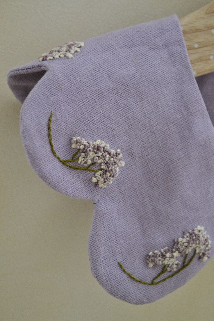 a purple cloth bag with white flowers on it and a wooden hanger hanging from the wall